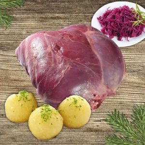 Rehbratenpaket: Reuhkeule mit Kartoffelknödeln und Rotkraut auf hellem Holzhintergrund